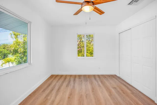 an empty room with a window and a ceiling fan
