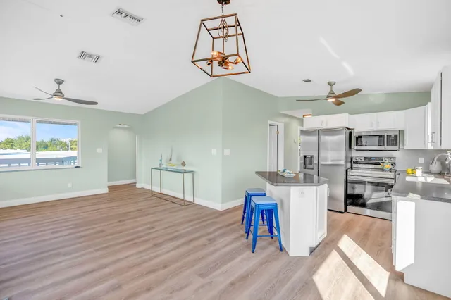 a kitchen with stainless steel appliances a sink a stove cabinets and a window