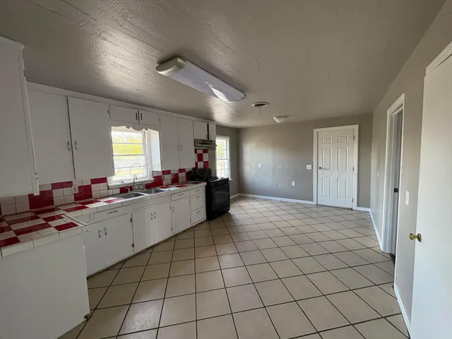 a large white kitchen with a sink and cabinets