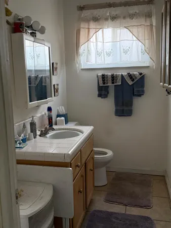 a bathroom with a granite countertop sink a toilet a mirror and a window