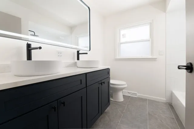 a bathroom with a granite countertop sink a toilet and a mirror