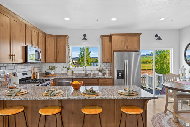 681 Island Road Morgan, UT 84050 - Photo 7 of 49 Kitchen featuring granite countertops, wood cabinetry, stainless steel appliances, and a subway tile backsplash