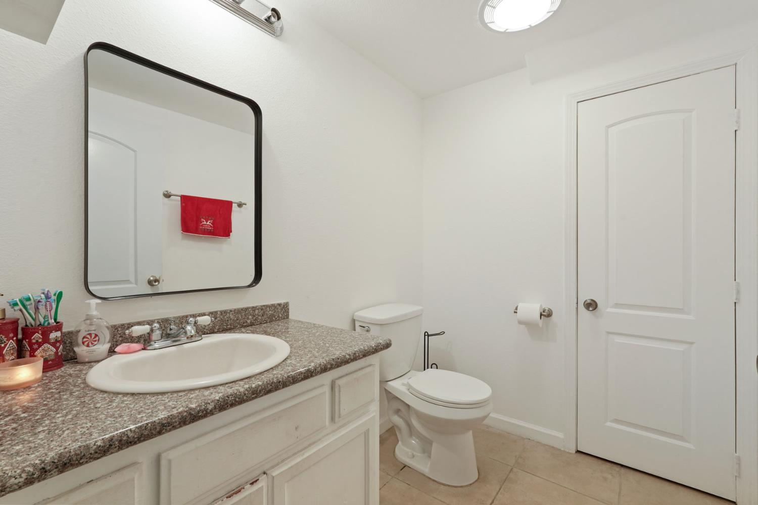 336 Locust Street Lodi, CA 95240 - Photo 6 of 31 a bathroom with a granite countertop toilet sink and mirror