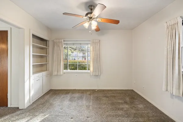 an empty room with windows and fan