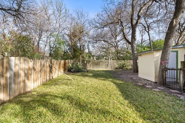 a view of backyard with wooden fence and a large tree