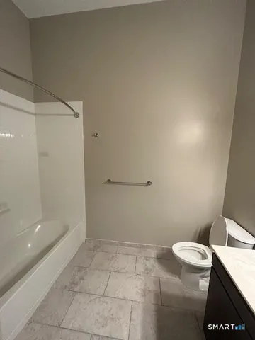 a bathroom with a granite countertop sink a toilet and a mirror