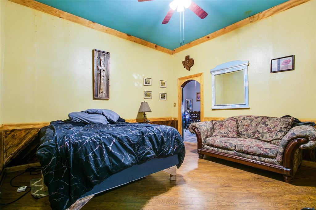 1303 North 7th Street Ballinger, TX 76821 - Photo 13 of 26 a living room with a bed furniture and a chandelier