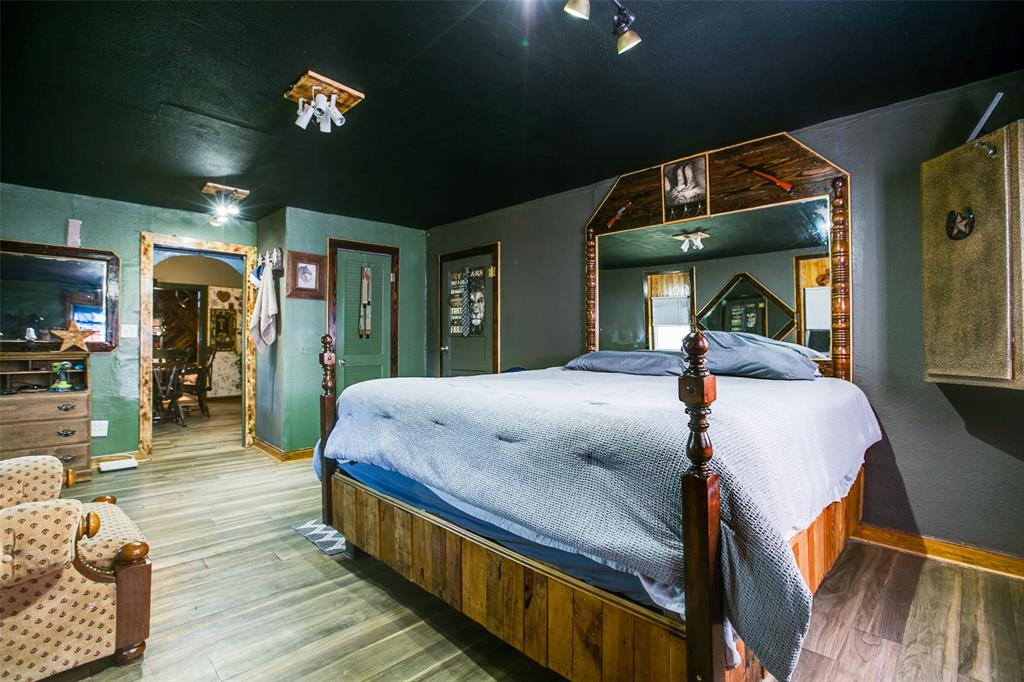 1303 North 7th Street Ballinger, TX 76821 - Photo 15 of 26 a spacious bedroom with a bed and a chandelier