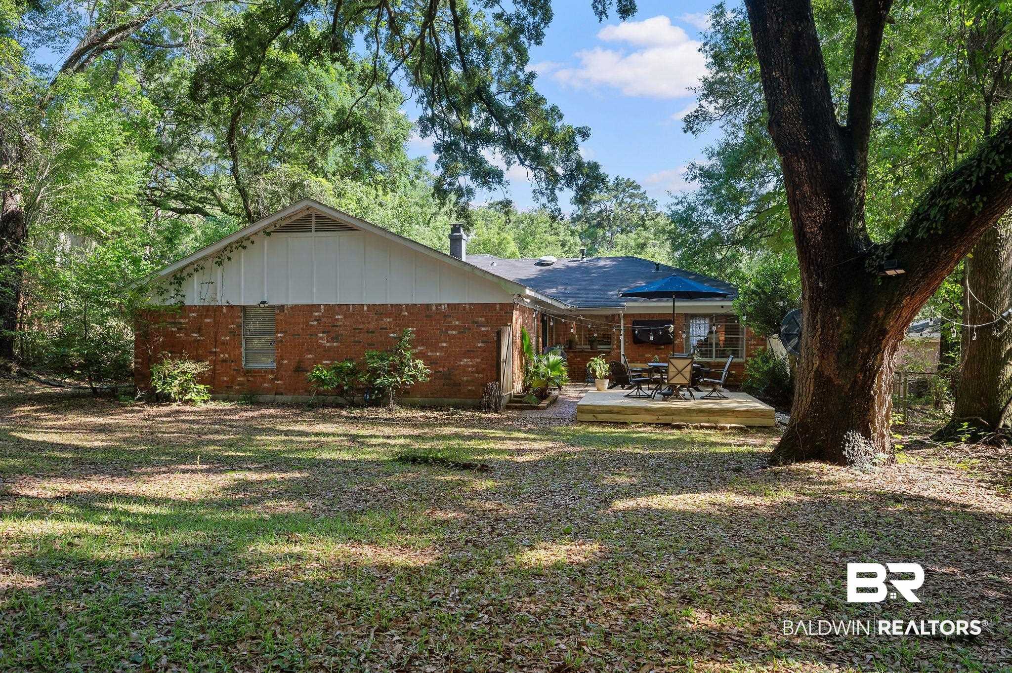 4724 Wicker Way Mobile, AL 36609 - Photo 29 of 36 Expansive backyard featuring a manicured lawn, mature trees, and a wooden deck