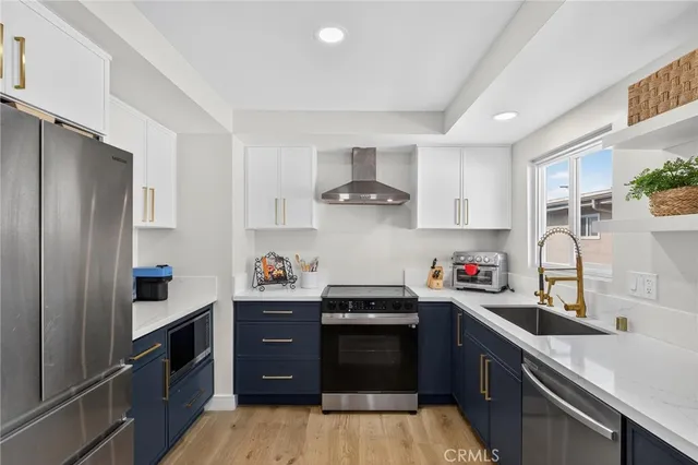 a kitchen with a sink dishwasher a refrigerator and a stove with wooden floor