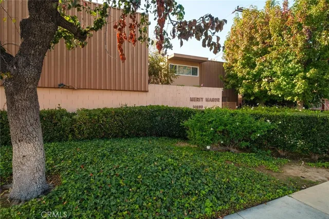 a view of a street with flower plants and large trees