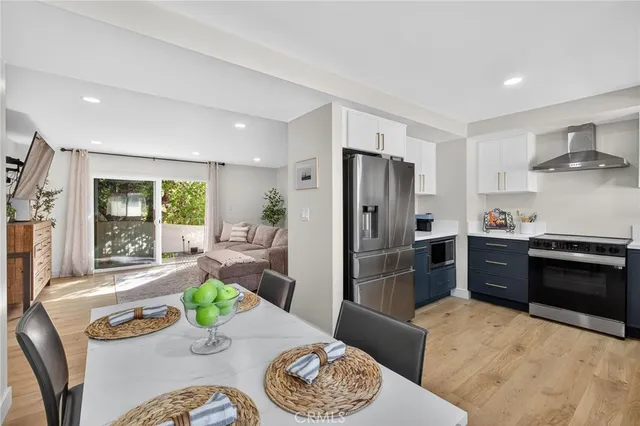 a kitchen with stainless steel appliances granite countertop a stove a refrigerator a sink a dining table and chairs