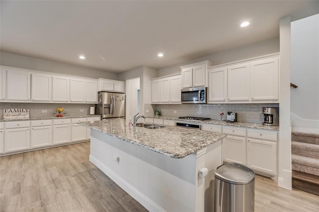 1271 Altuda Drive Forney, TX 75126 - Photo 11 of 35 a large kitchen with stainless steel appliances granite countertop a stove a sink a refrigerator and white cabinets with wooden floor