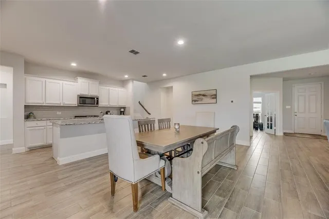 a kitchen with a table chairs a sink and a stove top oven with wooden floor