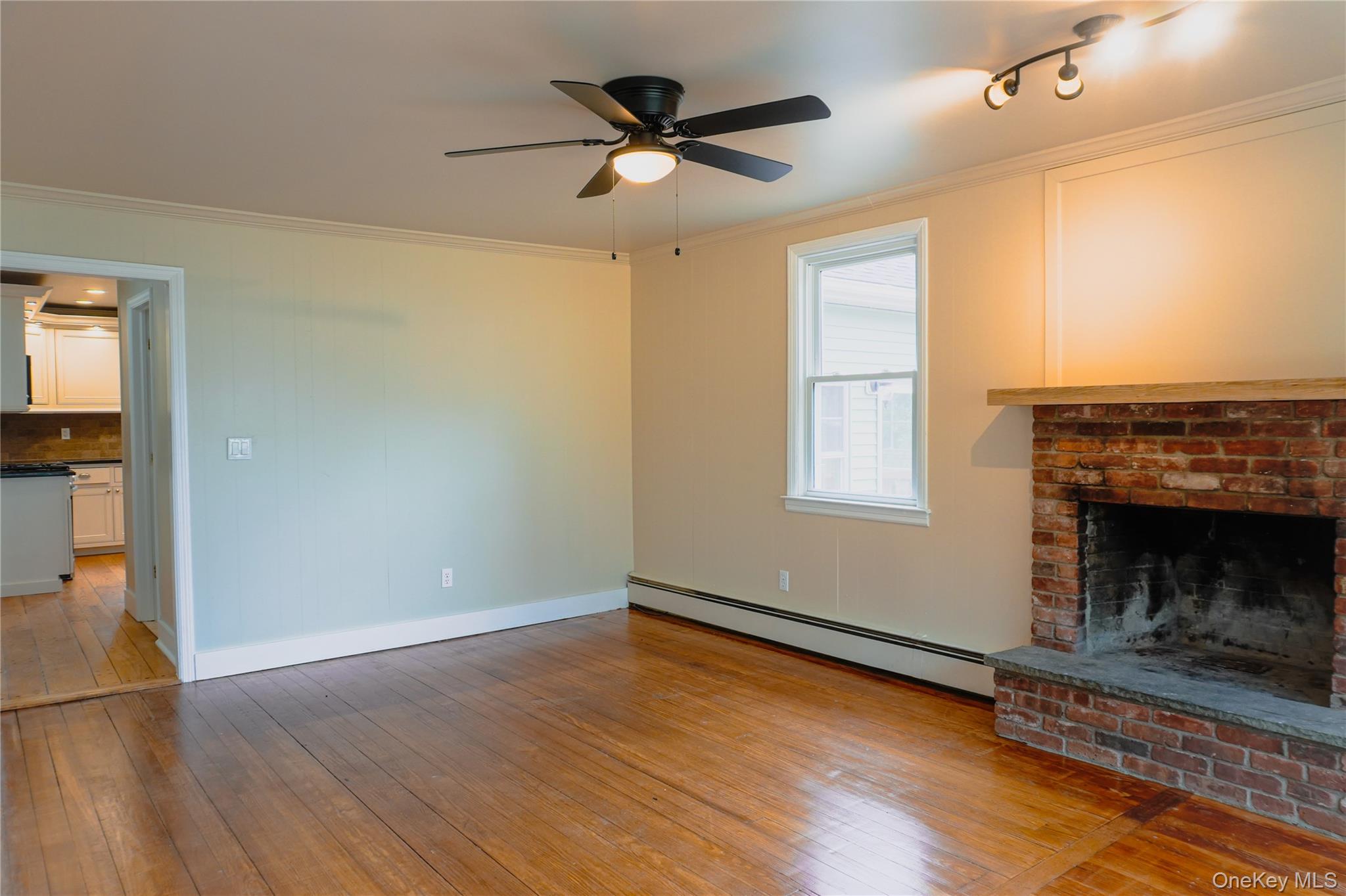 523 Shenandoah Road Hopewell Junction, NY 12533 - Photo 8 of 27 an empty room with wooden floor a ceiling fan a fireplace and windows