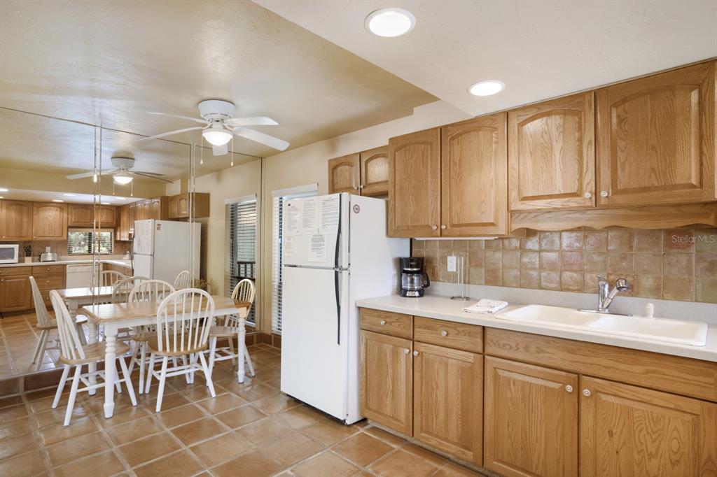 6157 Midnight Pass Road, Unit E22 Sarasota, FL 34242 - Photo 26 of 48 a kitchen with stainless steel appliances granite countertop a sink a stove a refrigerator with a dining table and chairs