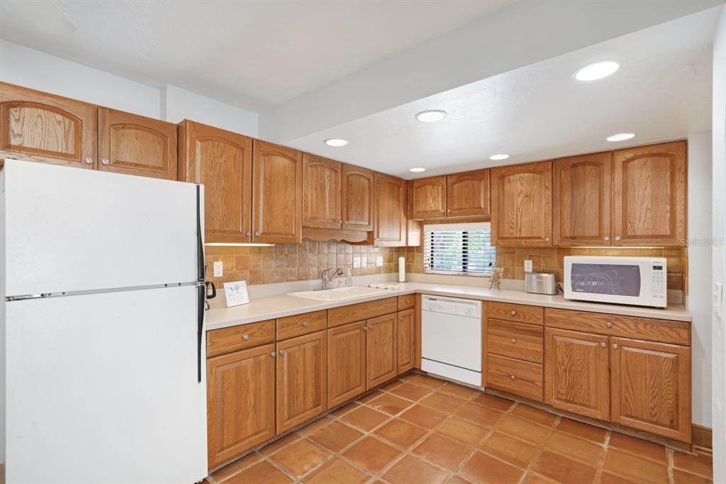 6157 Midnight Pass Road, Unit E22 Sarasota, FL 34242 - Photo 4 of 48 a kitchen with a sink a refrigerator and cabinets