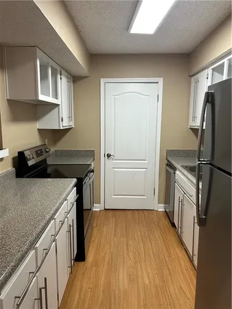 a kitchen with a refrigerator a sink and wooden floor