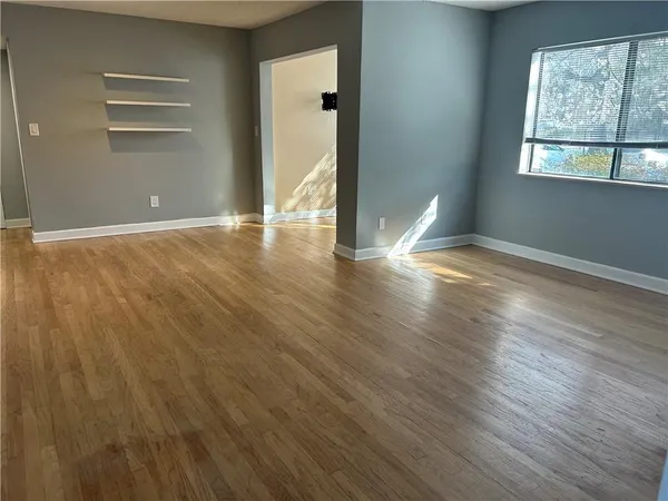 a view of empty room with wooden floor and fan