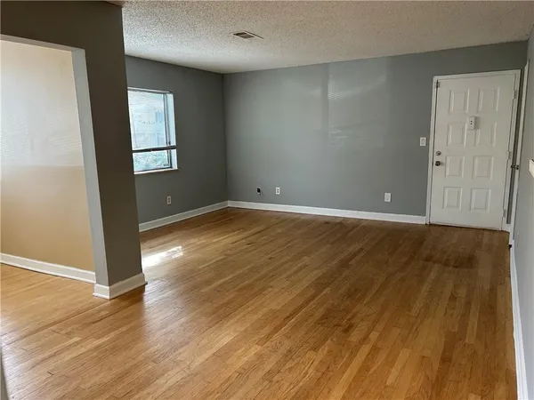 an empty room with wooden floor and windows