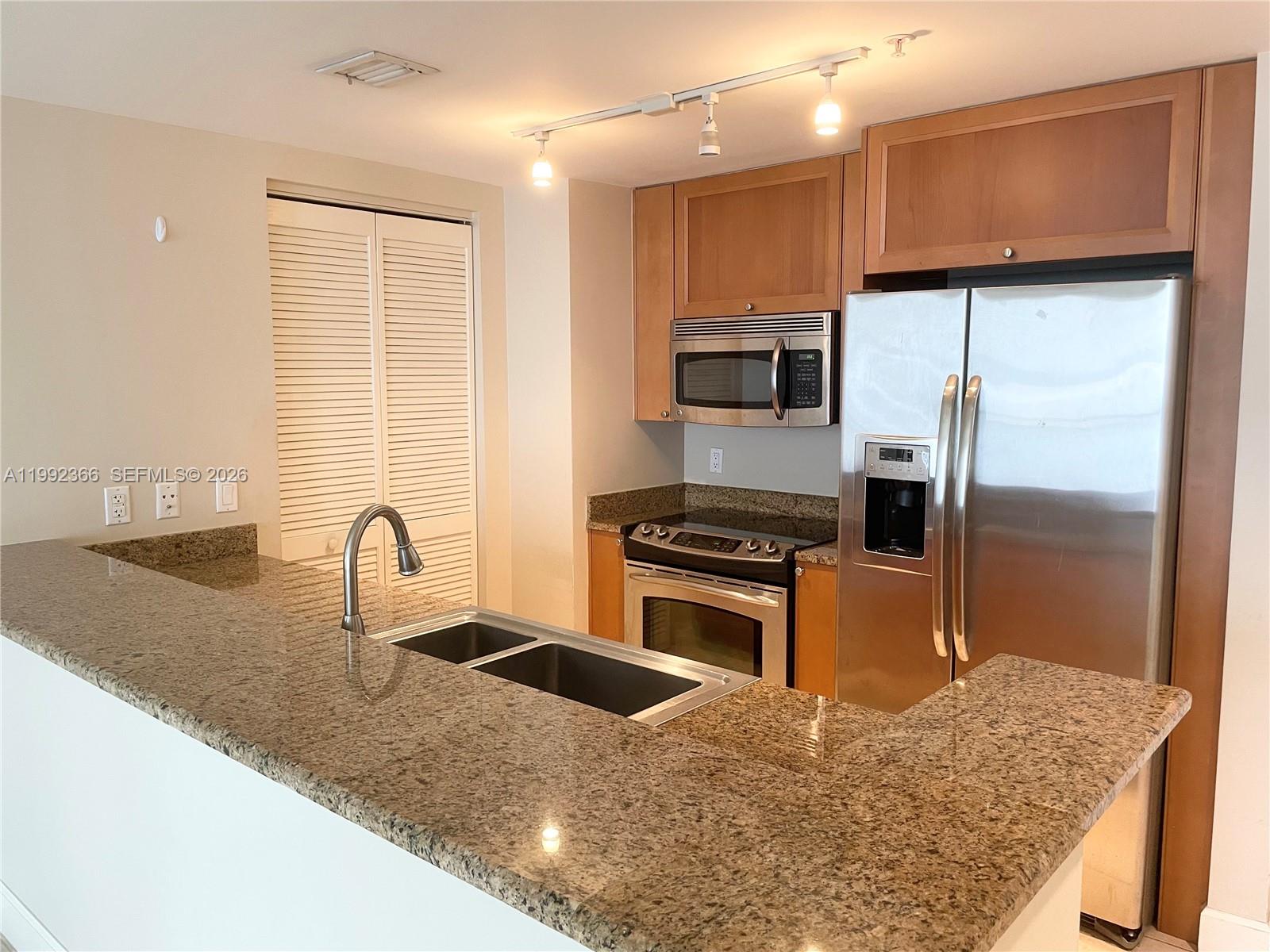 55 Merrick Way, Unit 702 Coral Gables, FL 33134 - Photo 6 of 17 a kitchen with stainless steel appliances granite countertop a sink refrigerator and microwave