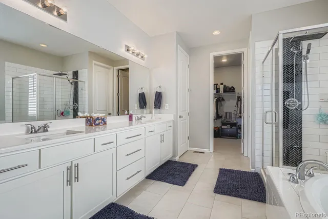 a spacious bathroom with a double vanity sink a mirror and a shower