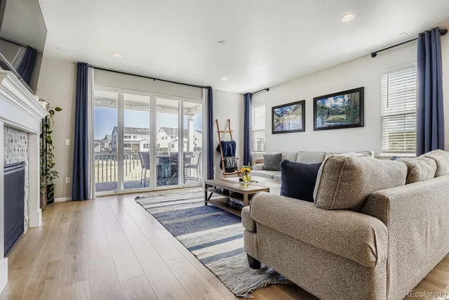 a living room with furniture large windows and wooden floor