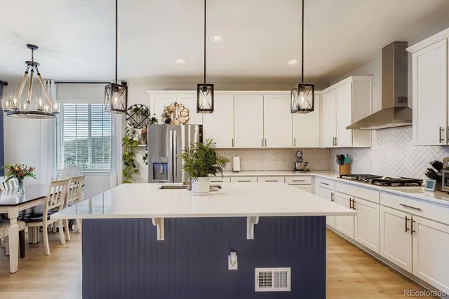 a kitchen with stainless steel appliances granite countertop a sink a stove a refrigerator a dining table and chairs