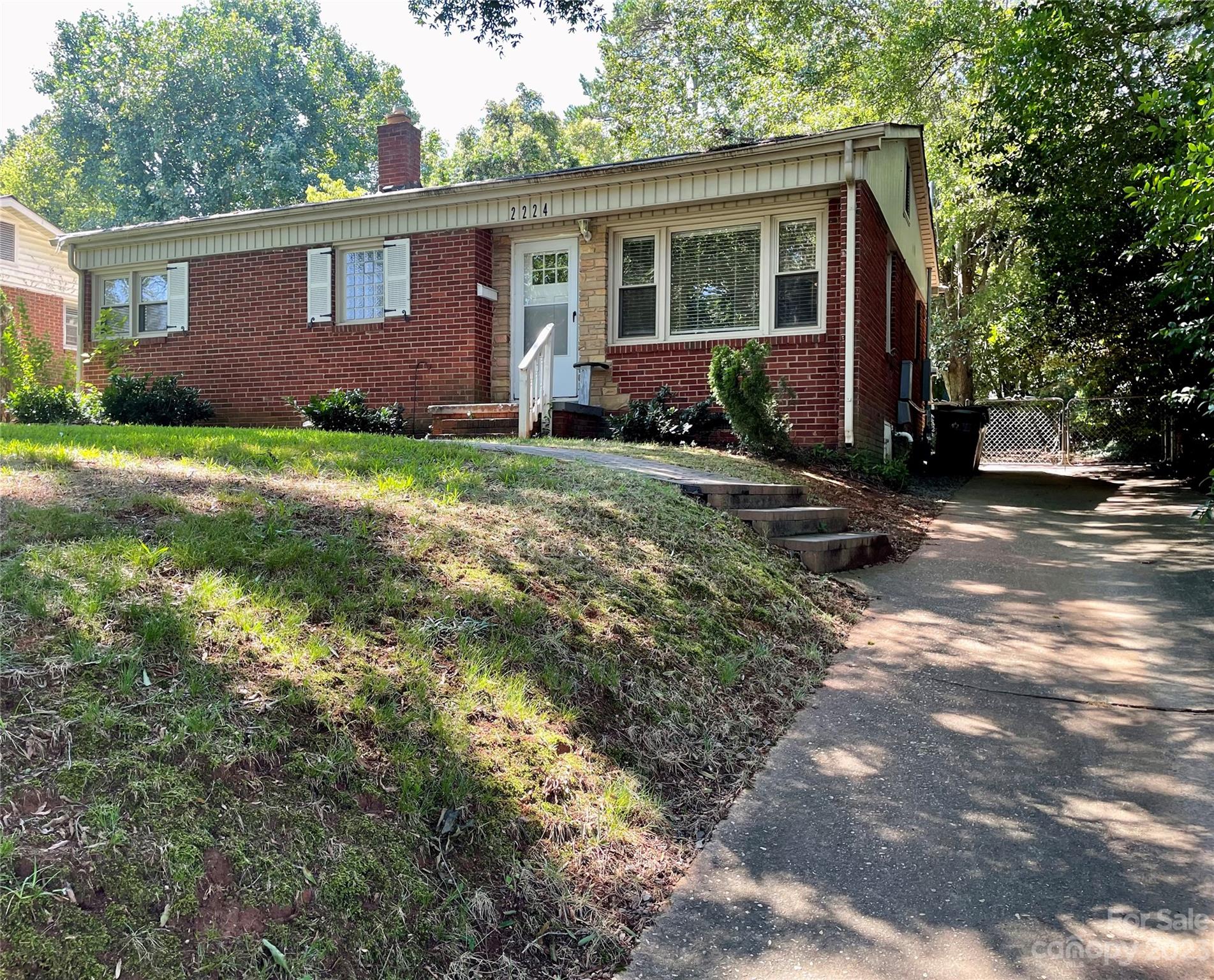 a front view of house with yard and trees in the background