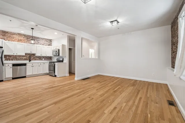 a view of a kitchen with a stove wooden cabinets and empty room