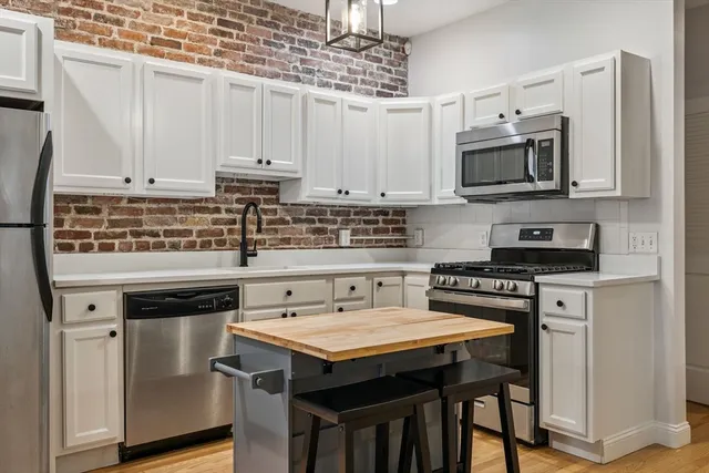 a kitchen with stainless steel appliances granite countertop a stove a refrigerator a sink a stove and white cabinets