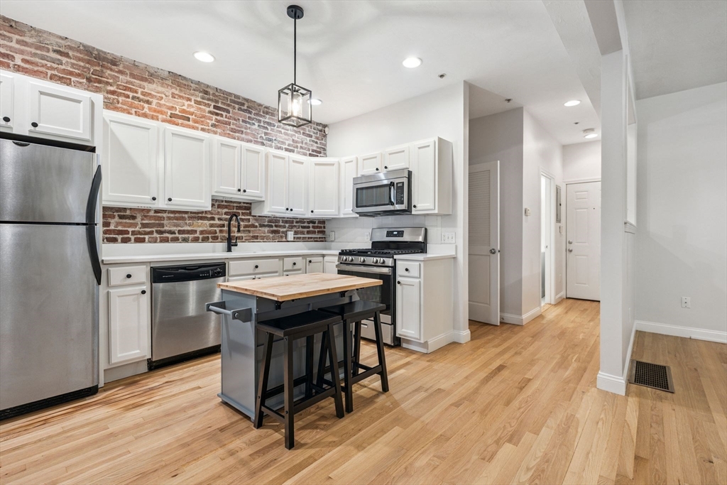 172 Cottage Street, Unit 2 Boston, MA 02128 - Photo 6 of 33 a kitchen with kitchen island a wooden floor and white appliances
