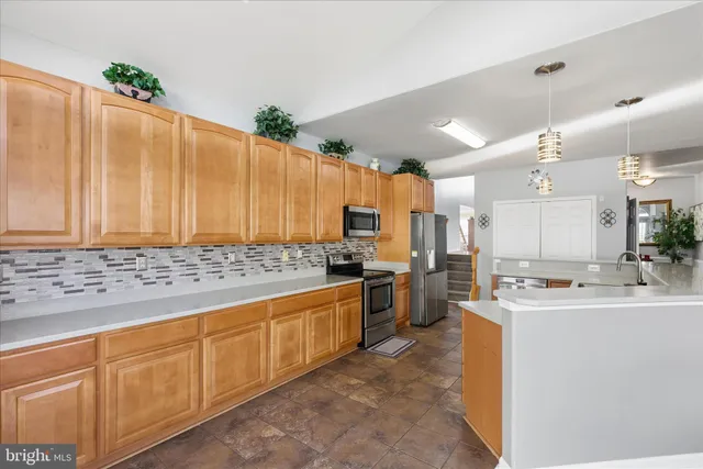 a large kitchen with kitchen island granite countertop a sink a stove counter space and cabinets