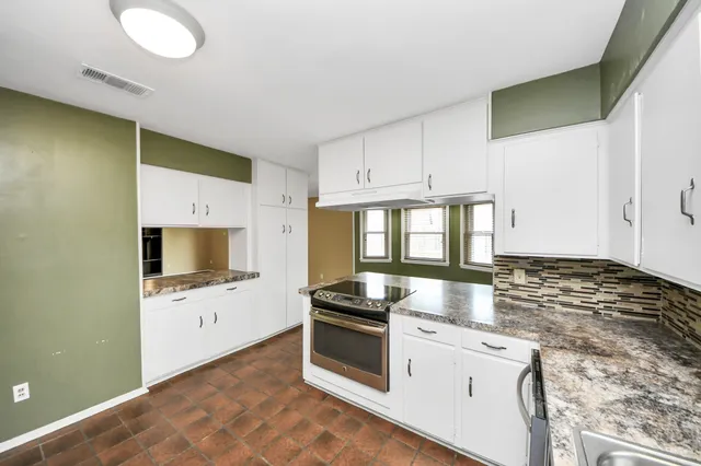 a kitchen with granite countertop a stove sink and microwave