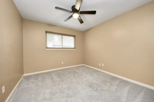 an empty room with a chandelier fan and windows