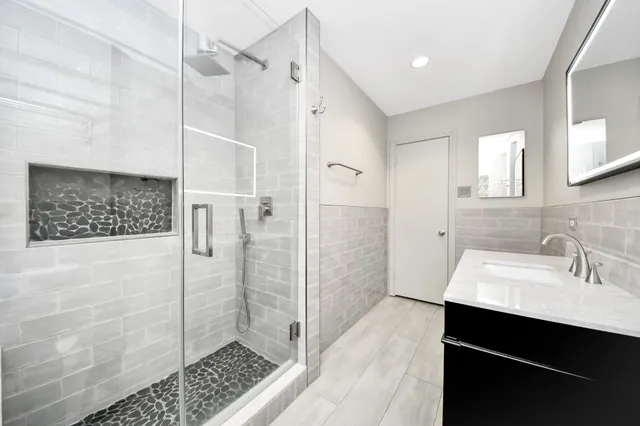 a bathroom with a sink shower and a mirror