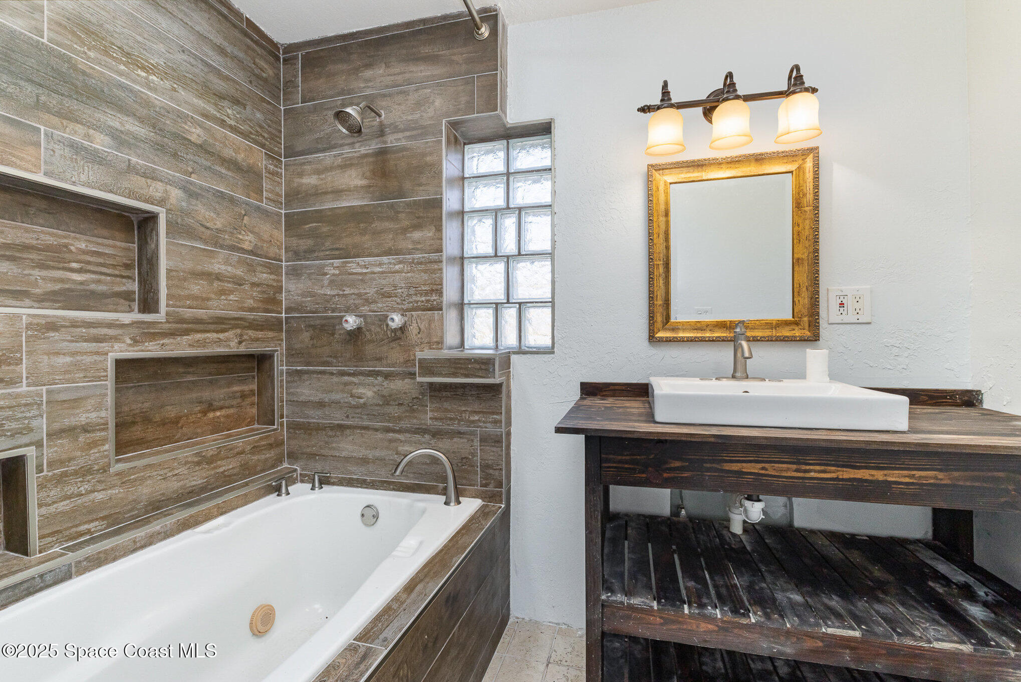 a bathroom with a tub a sink and a mirror