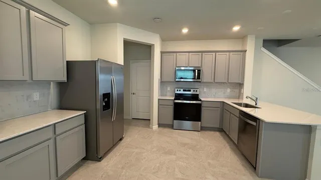 a kitchen with stainless steel appliances granite countertop a refrigerator stove and sink