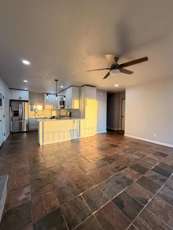 an empty room with wooden floor cabinet and windows