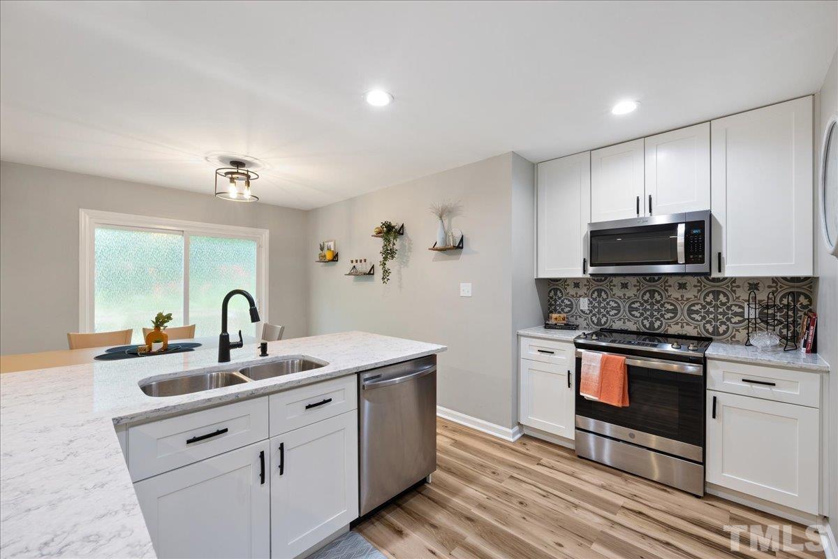 3101 Crandon Lane Raleigh, NC 27604 - Photo 8 of 18 a kitchen with stainless steel appliances granite countertop a stove a sink and a microwave