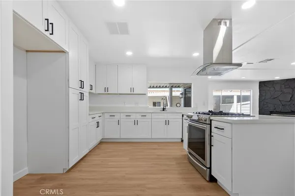 a kitchen with white cabinets and wooden floor