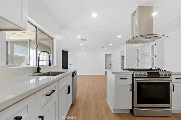 a kitchen with stainless steel appliances a stove and wooden floor
