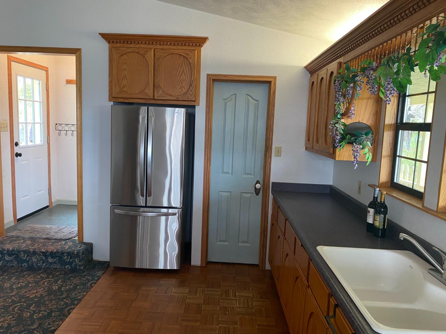5021 Banbury Cross Road Shingle Springs, CA 95682 - Photo 14 of 92 Kitchen view from the mud room and side door. The pantry door is easy reach for all your cooking necessities. Notice the double ceramic sink, spacious counter and window woodwork.