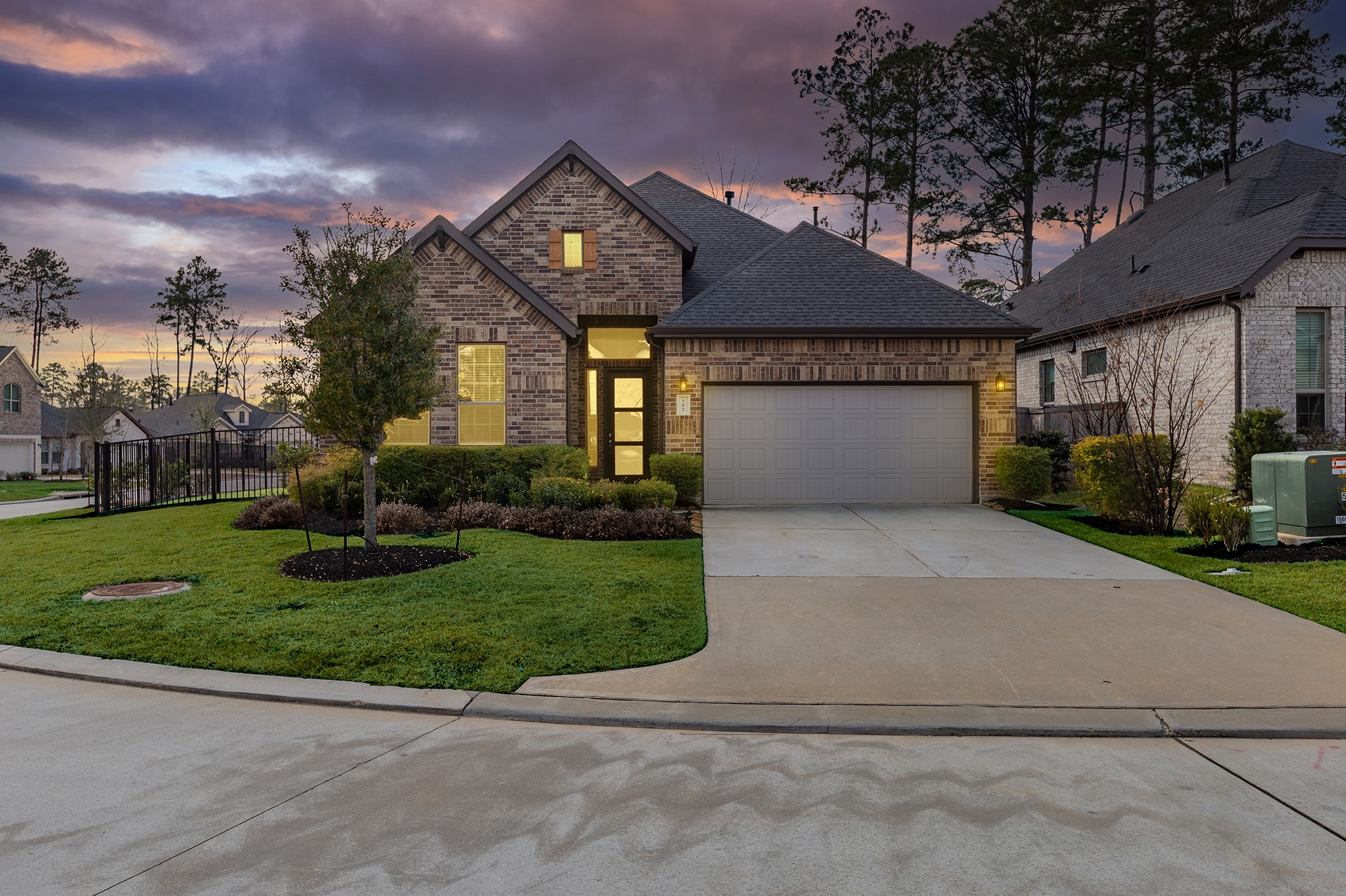 Striking twilight view highlighting the home’s brick exterior, clean lines, and welcoming curb appeal.