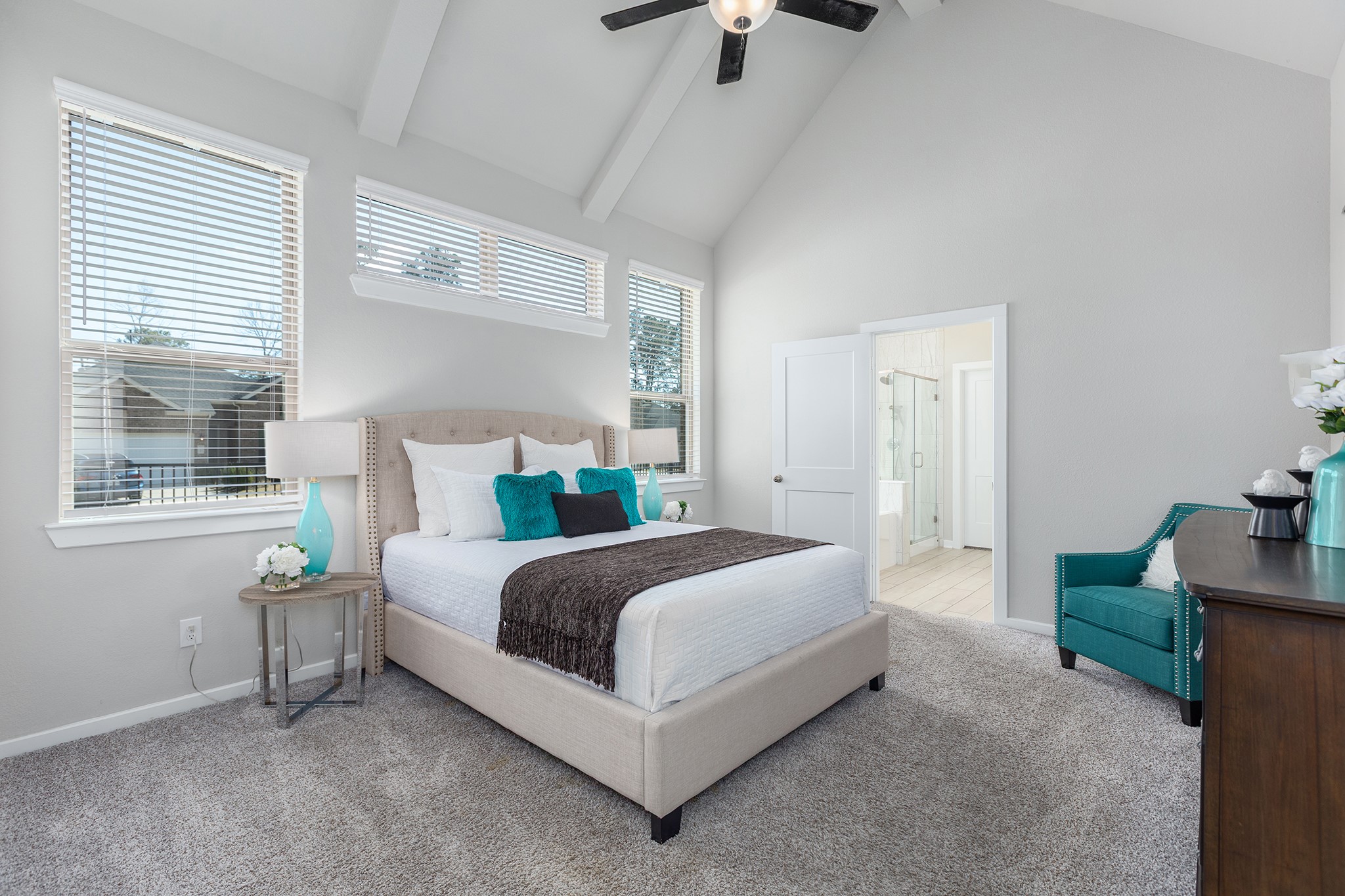 107 Yellow Perch Way Conroe, TX 77318 - Photo 21 of 44 Spacious primary bedroom featuring vaulted ceilings, neutral carpeting, and abundant natural light, with convenient access to the en-suite bathroom.