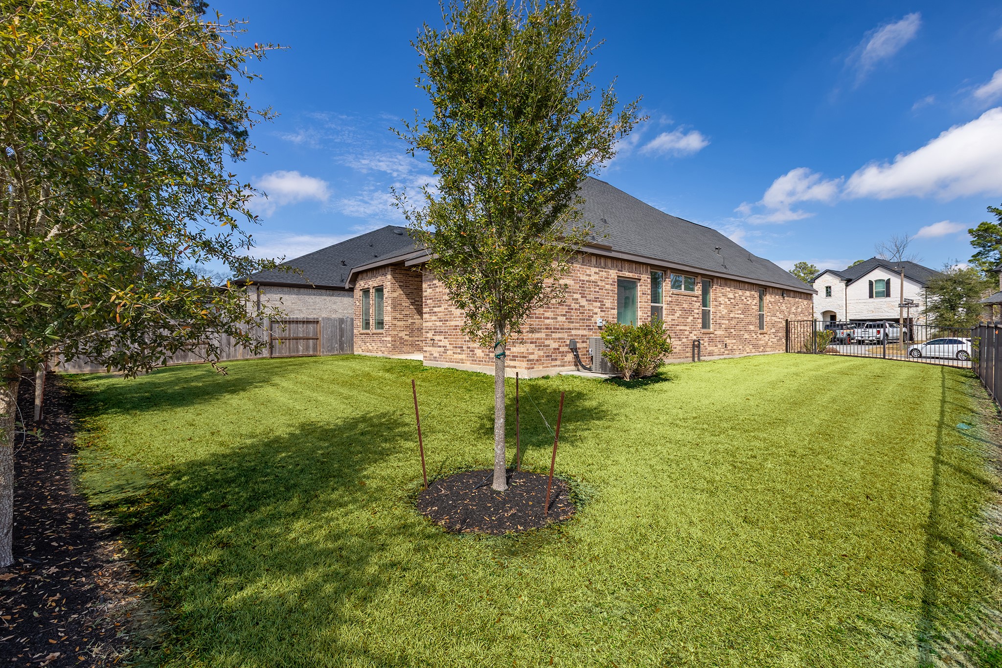 107 Yellow Perch Way Conroe, TX 77318 - Photo 34 of 44 This additional backyard view highlights open green space and landscaped surroundings, offering a comfortable setting for outdoor enjoyment.