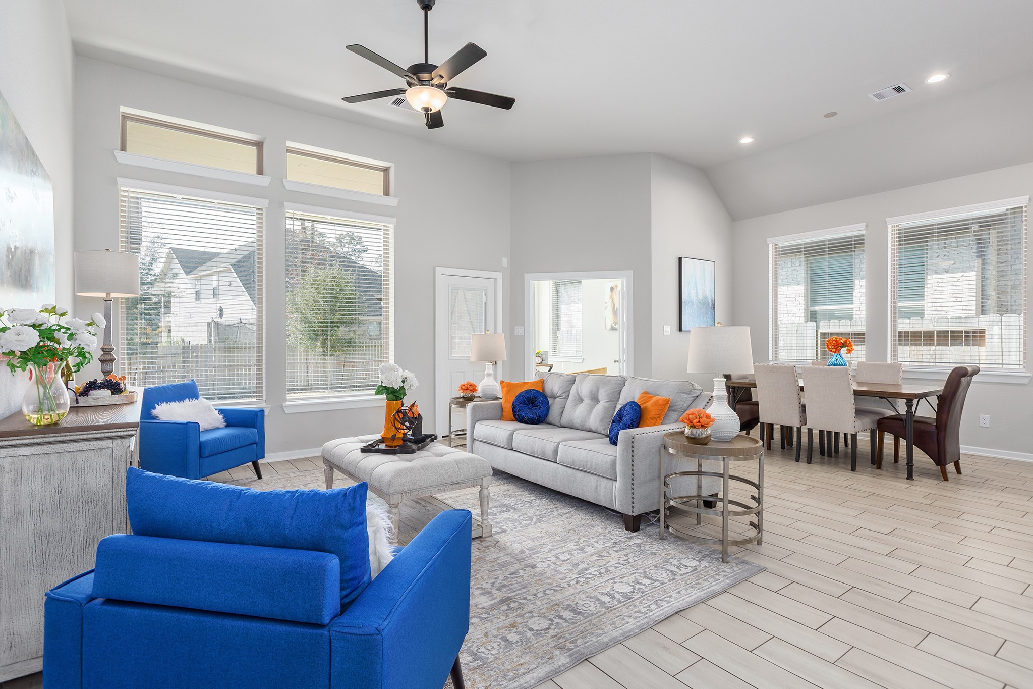 107 Yellow Perch Way Conroe, TX 77318 - Photo 10 of 44 Open-concept living area with vaulted ceilings, tile flooring, and expansive windows that overlook the backyard, offering clear sightlines and the opportunity to envision outdoor living or a future pool.