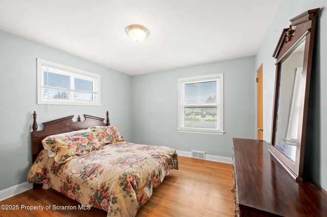 a bedroom with a bed and a window with wooden floor