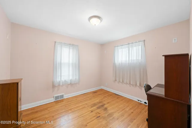 a view of an empty room with window and wooden floor