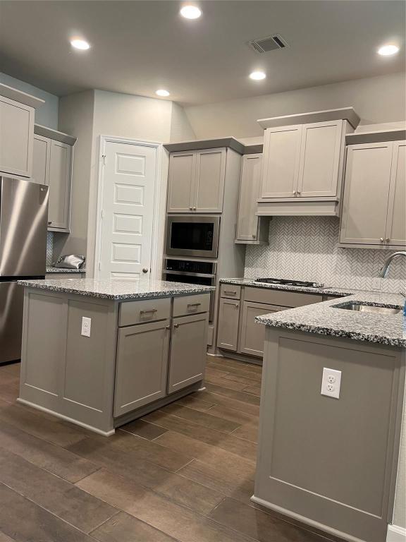 15707 Autumn Sun Conroe, TX 77302 - Photo 6 of 15 a kitchen with kitchen island granite countertop a sink a counter top space stainless steel appliances and cabinets